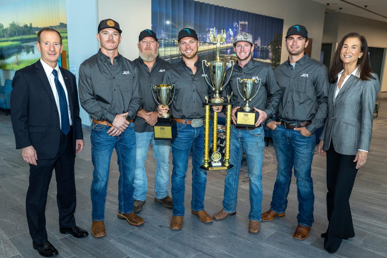 JEA Board Chair Joe DiSalvo (far left) and interim CEO and Managing Director Vickie Cavey (far right), are pictured with members of the utility's nationally recognized electric line worker competition team with recent trophies.