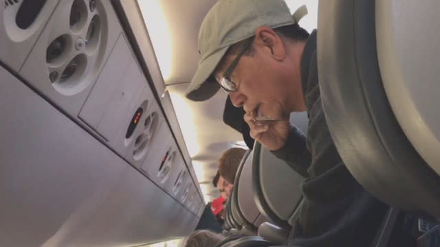 Captura de un nuevo video donde se ve al Dr. Dao hablando por teléfono antes de ser sacado a rastras del avión. (Vía Inside Edition/CBS)