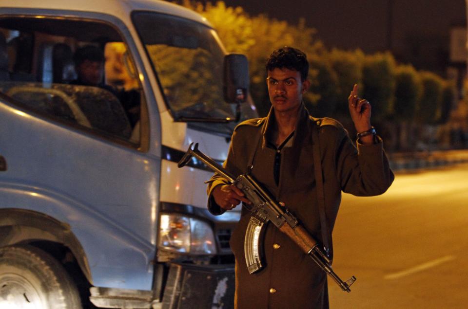 A policeman gestures in front of a barrier blocking the entrance to the central prison in Sanaa February 13, 2014. Seven people were killed when attackers mounted a bomb, grenade and gun assault on the main prison in Yemen's capital on Thursday in a failed attempt to free inmates, authorities and witnesses said. REUTERS/Mohamed al-Sayaghi (YEMEN - Tags: CIVIL UNREST CRIME LAW)