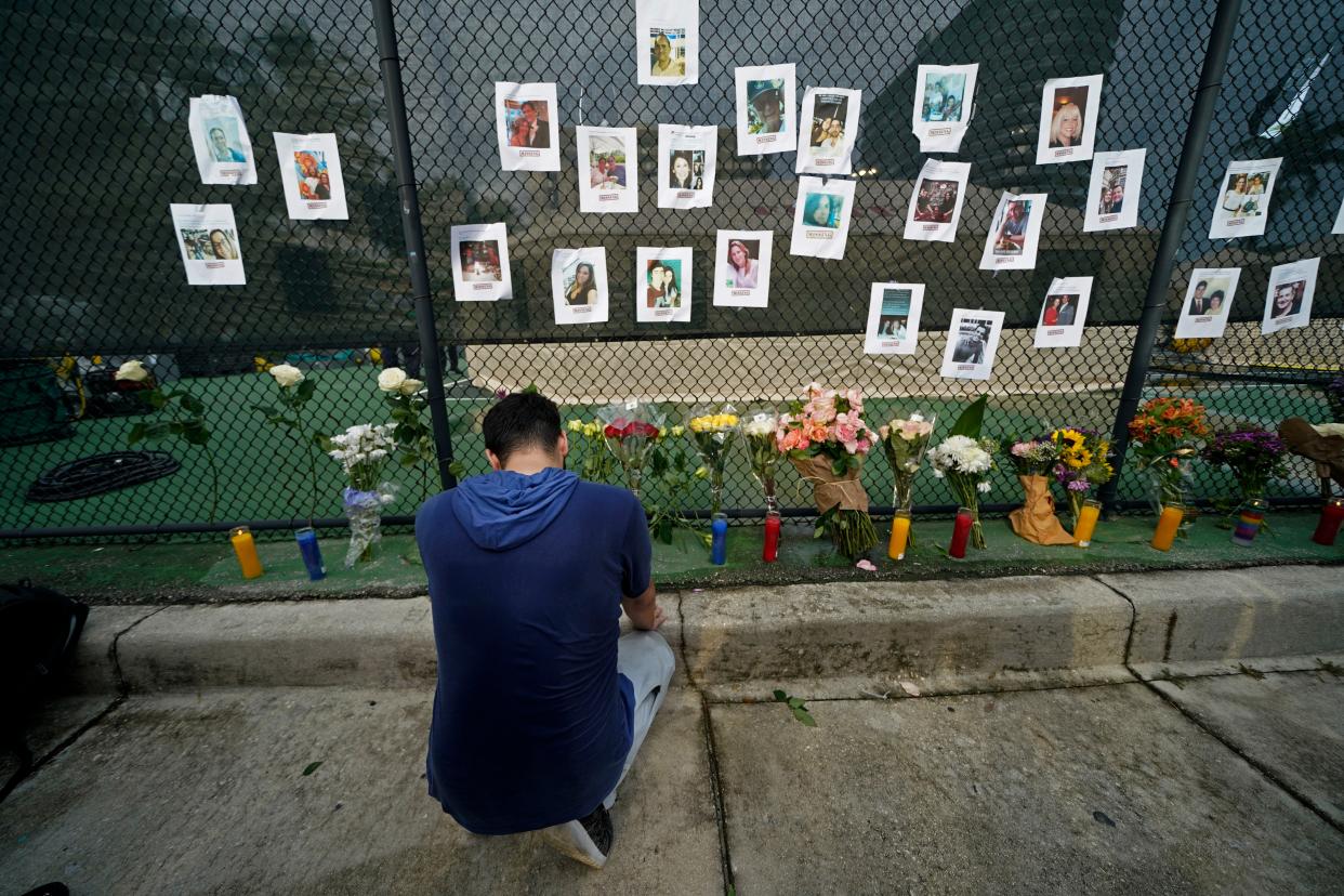 Leo Soto, who created this memorial with grocery stores donating flowers and candles, pauses in front of photos of some of the missing people that he put on a fence, near the site of an oceanfront condo building that partially collapsed in Surfside, Fla., Friday, June 25, 2021.