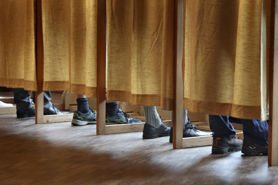 Voters stand in polling booths at a polling station in Schwangau, Germany, Sunday, Oct. 8, 2023. Two German states hold elections on Sunday at the halfway mark of Chancellor Olaf Scholz's unpopular national government, with polls showing the center-right opposition well ahead and Germany's interior minister facing an uphill struggle in a bid to become governor of her home region. (Karl-Josef Hildenbrand/dpa via AP)