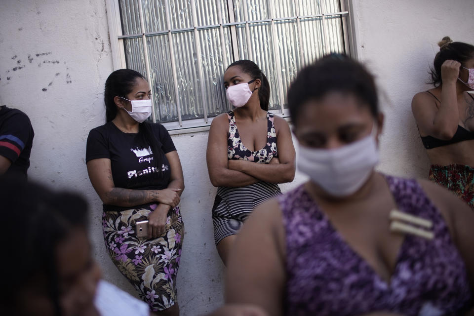 Residents wait to receive food donated by a non-governmental agency amid the new coronavirus pandemic, in the Mandela slum, in Rio de Janeiro, Brazil, Tuesday, April 21, 2020. Many of the residents who are informal workers are receiving food donations as they are unable to work because of the widespread shutdowns to contain the the spread of COVID-19. (AP Photo/Silvia Izquierdo)