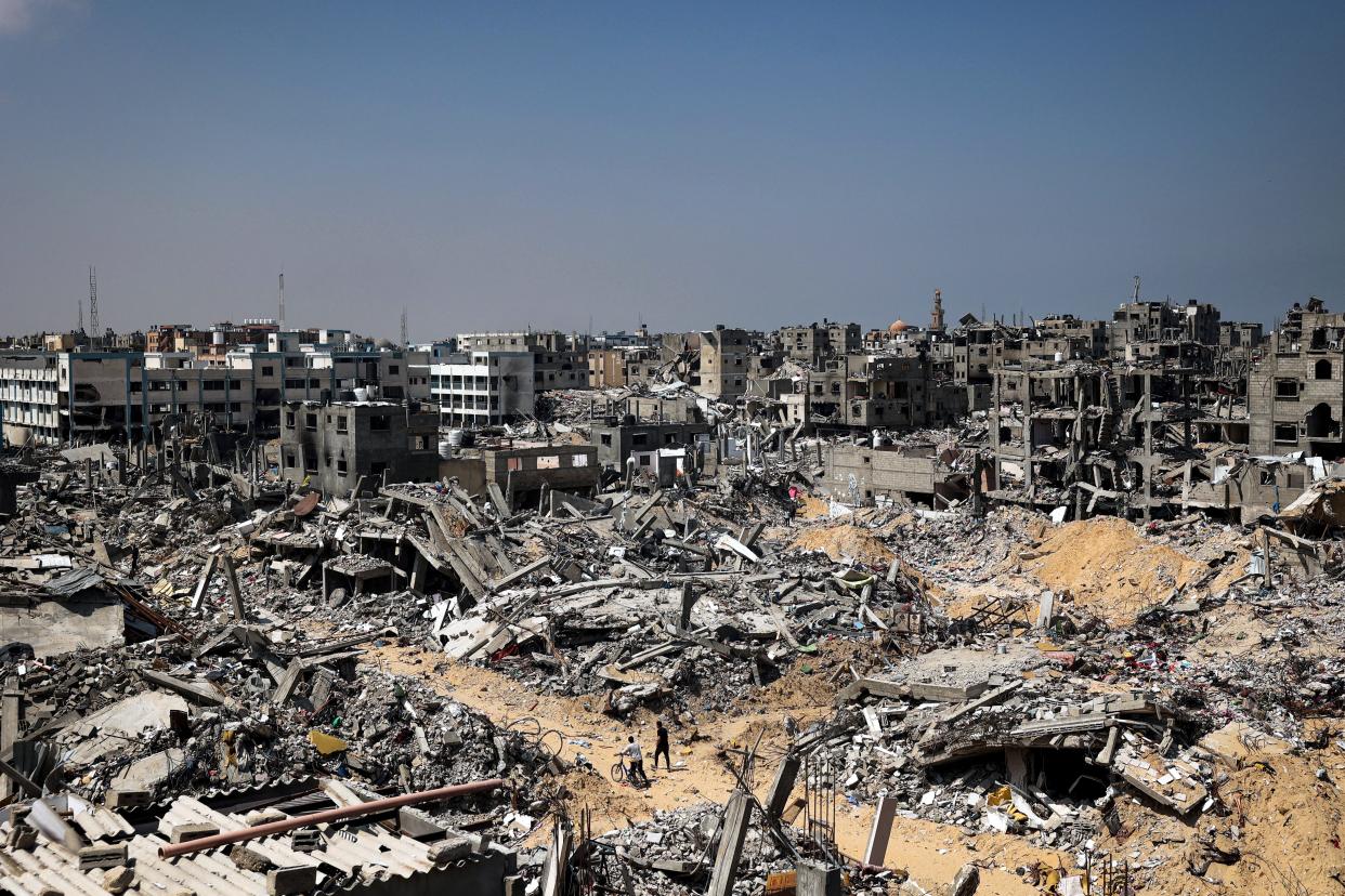 People walk amid the rubble of buildings destroyed during Israeli bombardment in Khan Yunis, on the southern Gaza Strip on April 16, 2024, as fighting continues between Israel and the Palestinian militant group Hamas.
