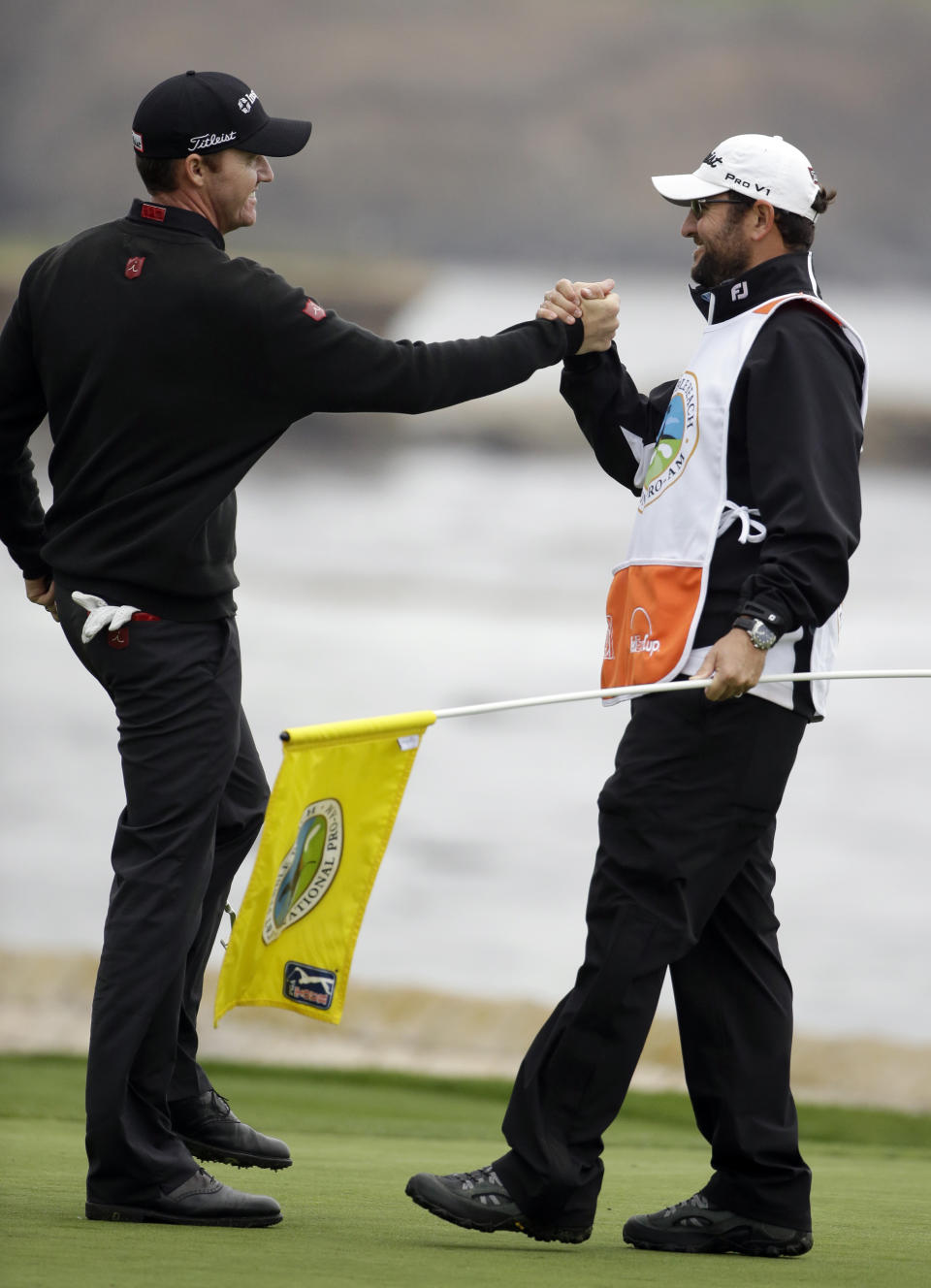 Jimmy Walker, left, celebrates with his caddie Andy Sanders on the 18th green on Sunday, Feb. 9, 2014, after winning the AT&T Pebble Beach Pro-Am golf tournament in Pebble Beach, Calif. (AP Photo/Eric Risberg)