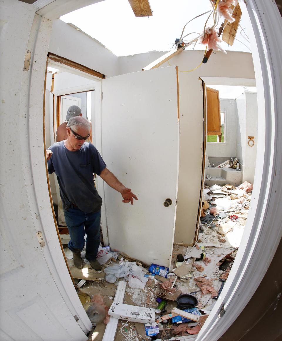 In this image made with a fisheye lens, Rickey Shelton looks at the hallway on Tuesday, April 29, 2014, where he and his wife, Silver Shelton, took shelter when their home was destroyed in Fayetteville, Tenn. Around 50 tornadoes ravaged the South Monday, according to the National Oceanic and Atmospheric Administration's Storm Prediction Center. (AP Photo/Mark Humphrey)