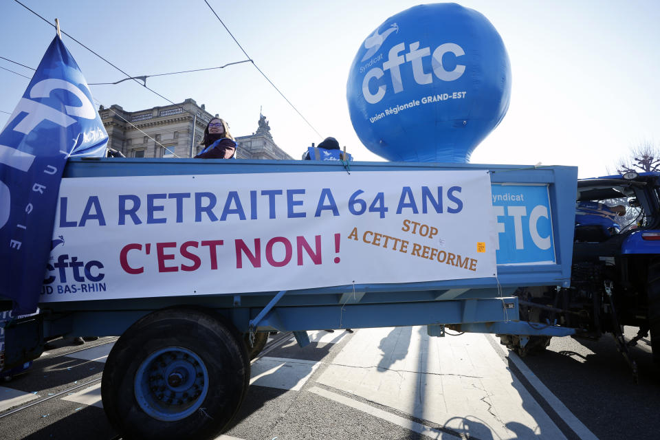 A banner is put on a farm trailer reading "Retirement at 64 years Old is No, Stop This Reform" during a march against pension reforms in Strasbourg, eastern France, Tuesday, Feb. 7, 2023. Public transportation, schools and electricity, oil and gas supplies were disrupted on Tuesday in France as demonstrators were taking to the streets for a third round of nationwide strikes and protests against the government's pension reform plans. (AP Photo/Jean Francois Badias)