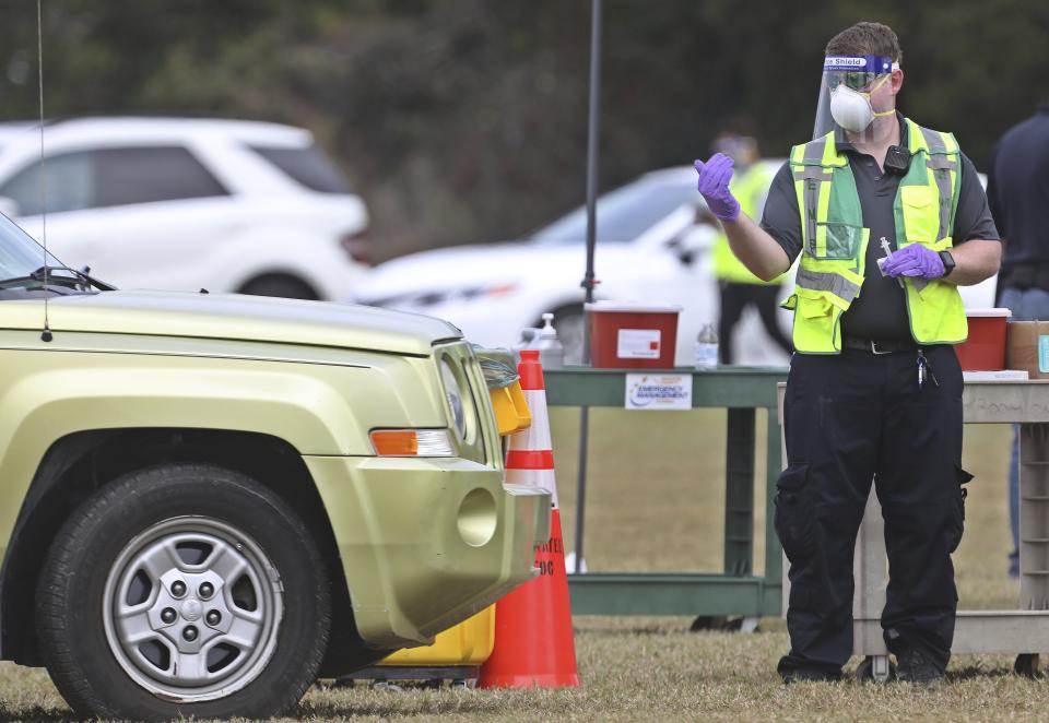 A health worker directs a vehicle before administering a COVID-19 vaccine to one of about 300 people to get vaccinated, Wednesday, Dec. 30, 2020, at the Manatee County Public Safety Center in Bradenton, Fla. (Scott Keeler/Tampa Bay Times via AP)