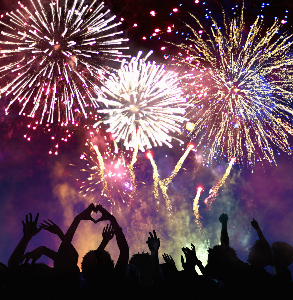 Silhouetted crowd enjoying a vibrant fireworks display in the night sky