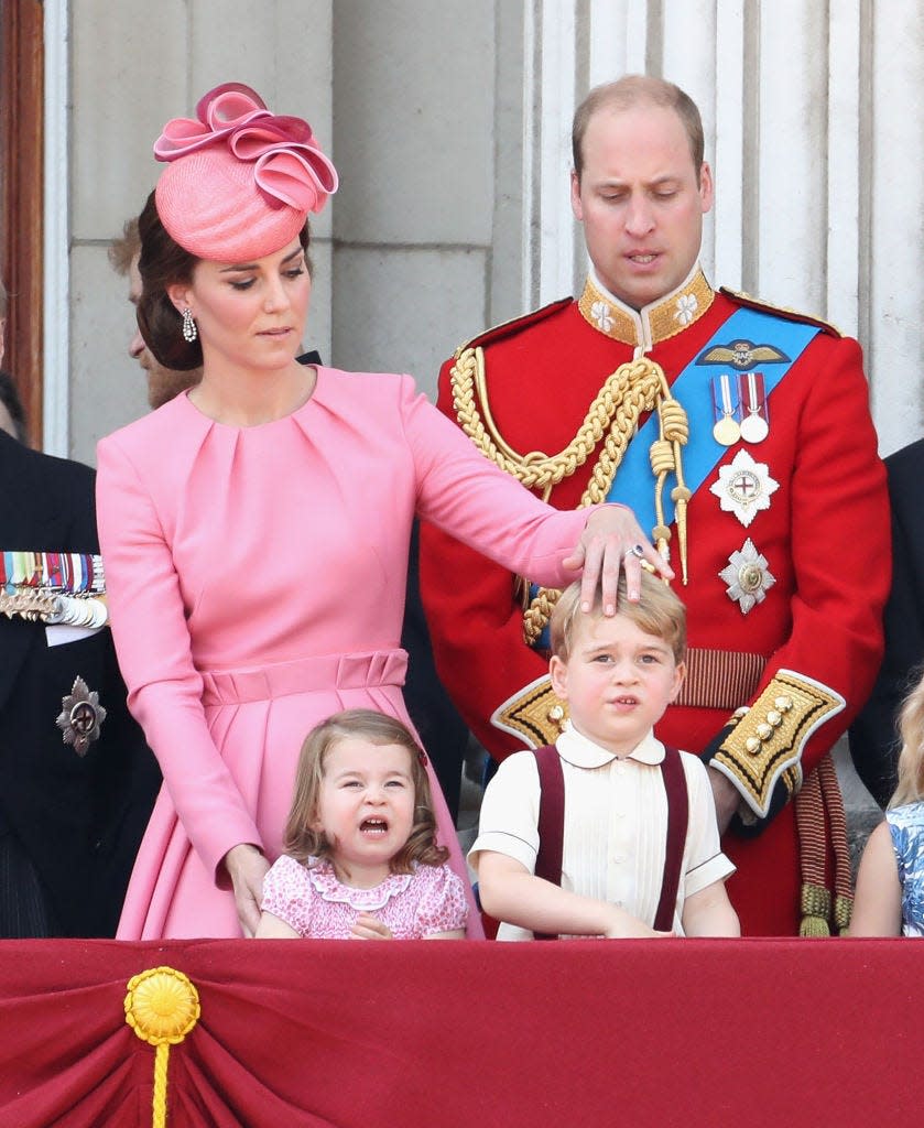 Prince William and Kate Middleton, who is fixing Prince George's hair, on the balcony of Buckingham Palace.