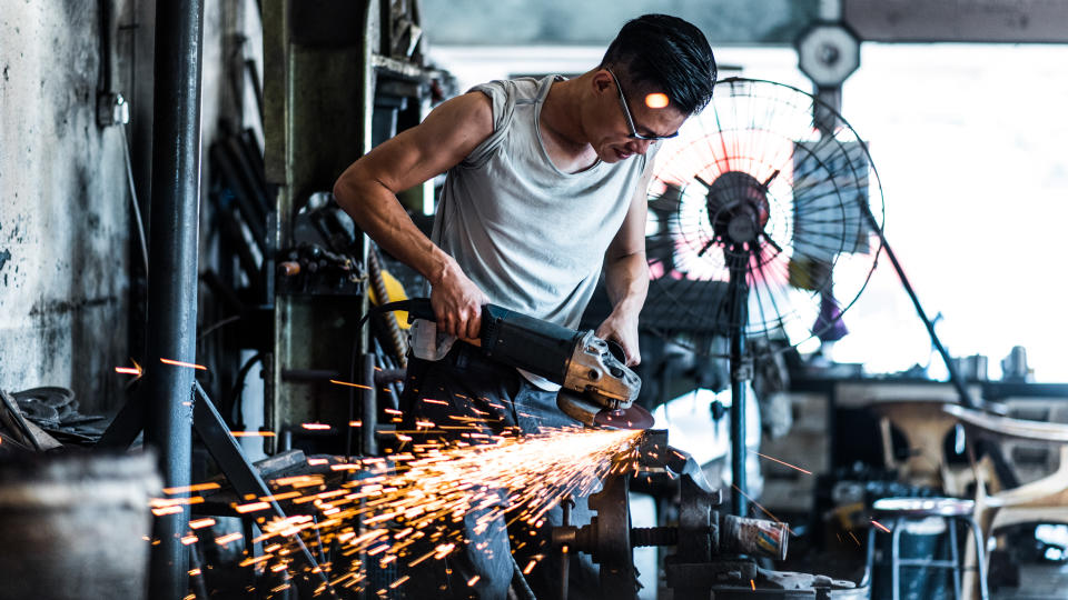 Asian blacksmith working with a grinder.