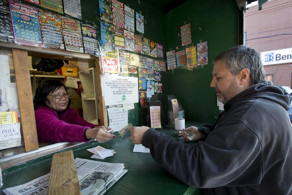 Norn Phneo sells Powerball tickets to Billy Fulginiti, of Philadelphia for himself and his coworkers, Wednesday, Nov. 28, 2012, in Philadelphia. (AP Photo/Matt Rourke)