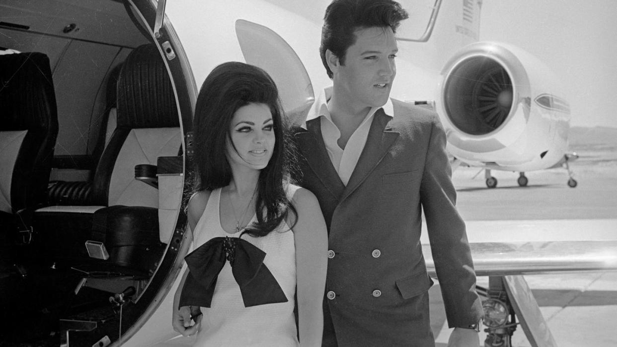 elvis and priscilla presley posing near airplane