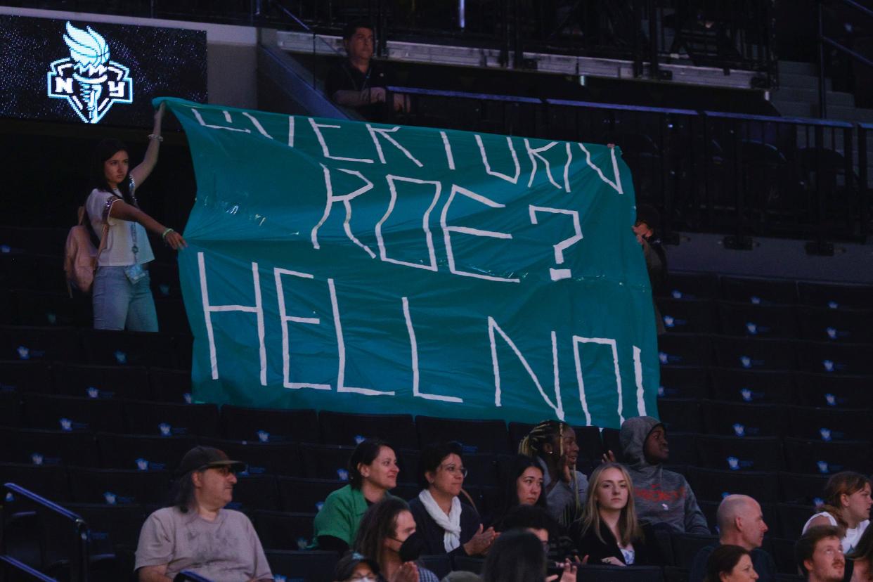 Protesters unfurl a banner that reads "Overturn Roe? Hell No!" during a New York Liberty game at the Barclays Center.