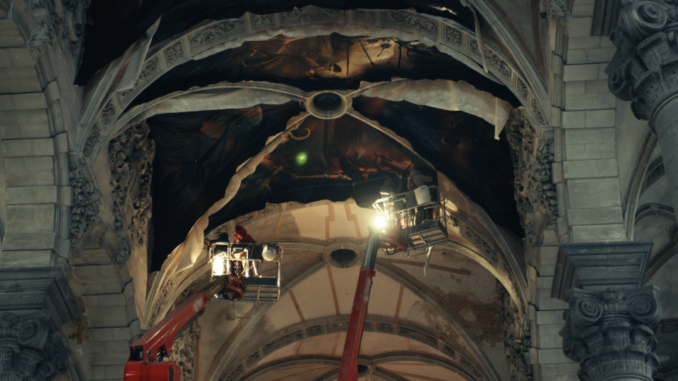 Painters work on the ceiling of a cathedral.