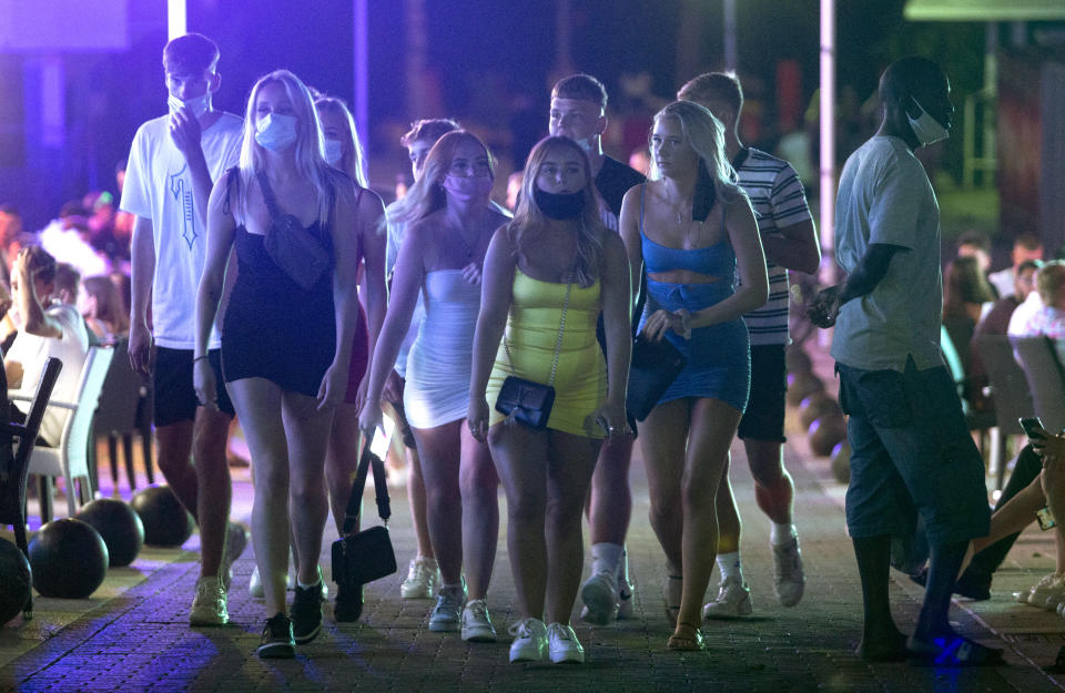 Tourists walk at the resort of Magaluf on the Spanish Balearic island of Mallorca, Spain, Thursday morning, July 16, 2020. Authorities in Spain's Balearic Islands are pulling the plug on endless drunken nights to the beat of techno music by closing bars and nightclubs in beachfront areas popular with young and foreign visitors. (AP Photo/Joan Mateu)