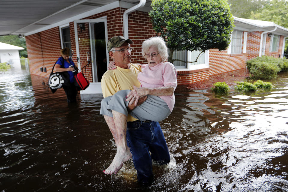 FILE - In this Sept. 17, 2018 file photo, Bob Richling carries Iris Darden, 84, out of her flooded home as her daughter-in-law, Pam Darden, gathers her belongings in the aftermath of Hurricane Florence in Spring Lake, N.C. (AP Photo/David Goldman)