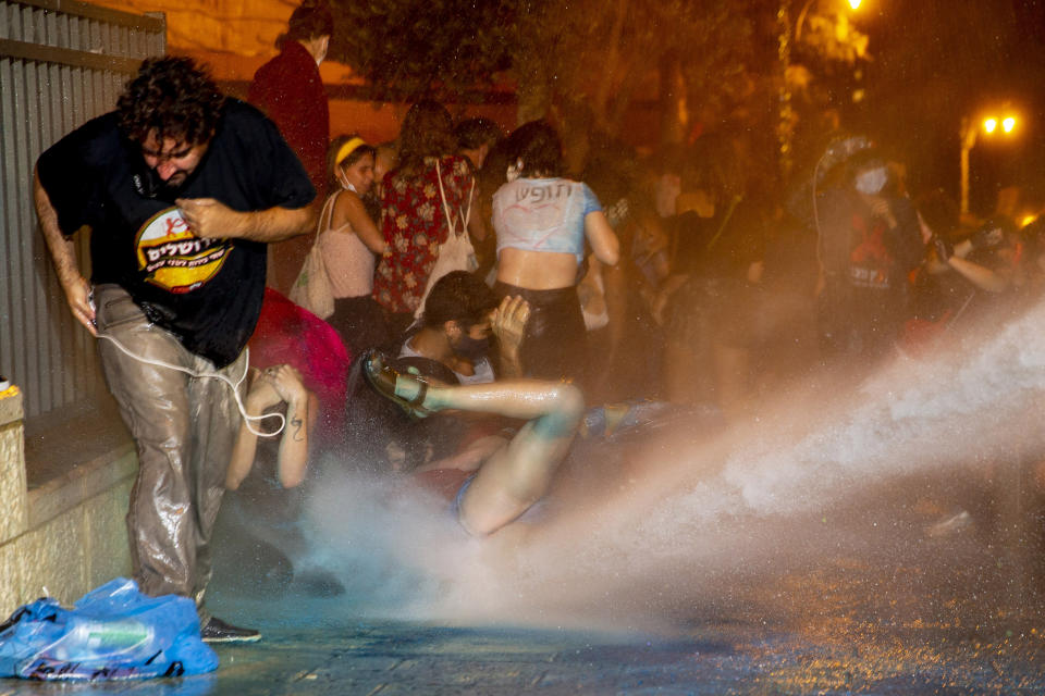 Police use a water cannon to disperse demonstrators during a protest against Israel's Prime Minister Benjamin Netanyahu outside his residence in Jerusalem, early Wednesday, July 22, 2020. Protesters demanded that the embattled leader resign as he faces a trial on corruption charges and grapples with a deepening coronavirus crisis. (AP Photo/Ariel Schalit)