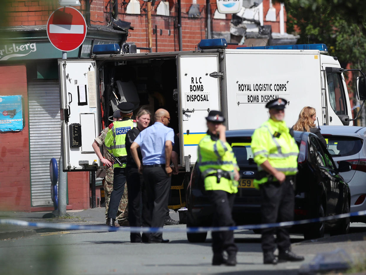 Armed officers at a cordon in Quantock Close, Moss Side, as fresh raids are carried out: PA