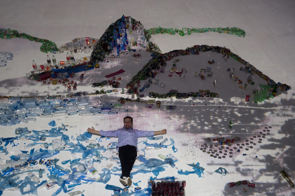 Brazilian artist Vik Muniz poses for a photo as he lies on his "Landscape" project that uses waste to recreate the image of Guanabara Bay in Rio de Janeiro, Brazil, Saturday, June 16, 2012. Muniz's project recreates city landmarks with recyclable materials donated by the public, who will be able to take their waste to the installation's tent between June 15 and 22, on the sidelines of the UN Conference on Sustainable Development, or Rio+20. (AP Photo/Silvia Izquierdo)