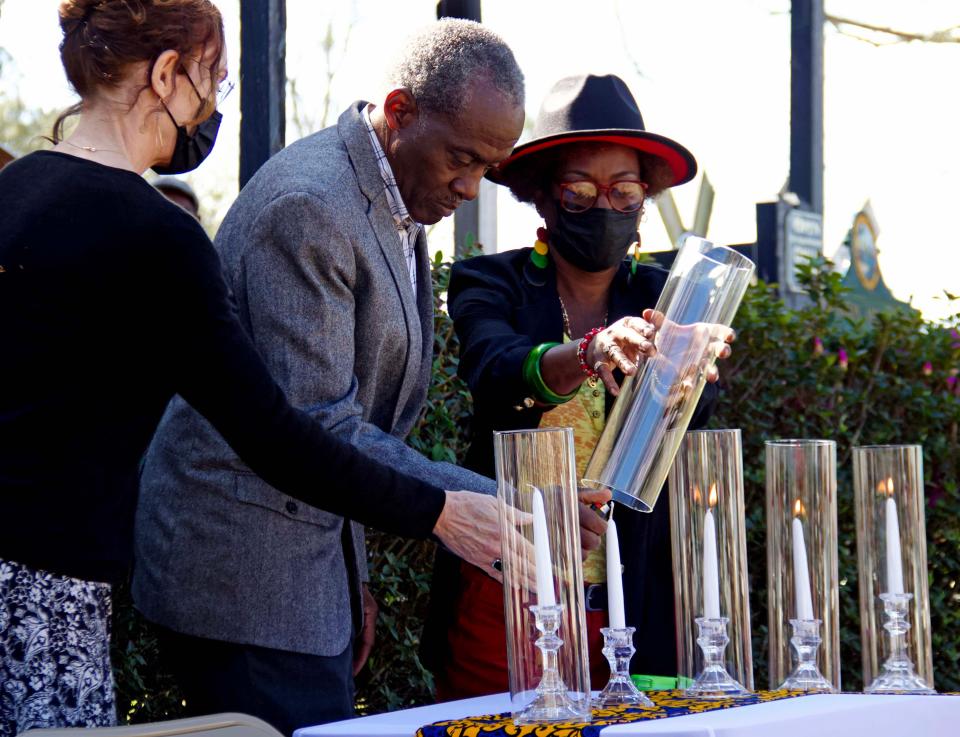 Kerry Dowd (left), John Ronnie Nix (middle), and Monique Taylor (right) light candles in rememberance at the Soil Collection Ceremony in Waldo on Saturday. “The Equal Justice Initiative has partnered with community coalitions across the nation to collect soil from every lynching site as an act of remembrance and commitment to honoring the victims of this horrific era of terror,” the Rev. Carl Smart said. The jars will be on display at the Legacy Museum in Montgomery, Alabama.