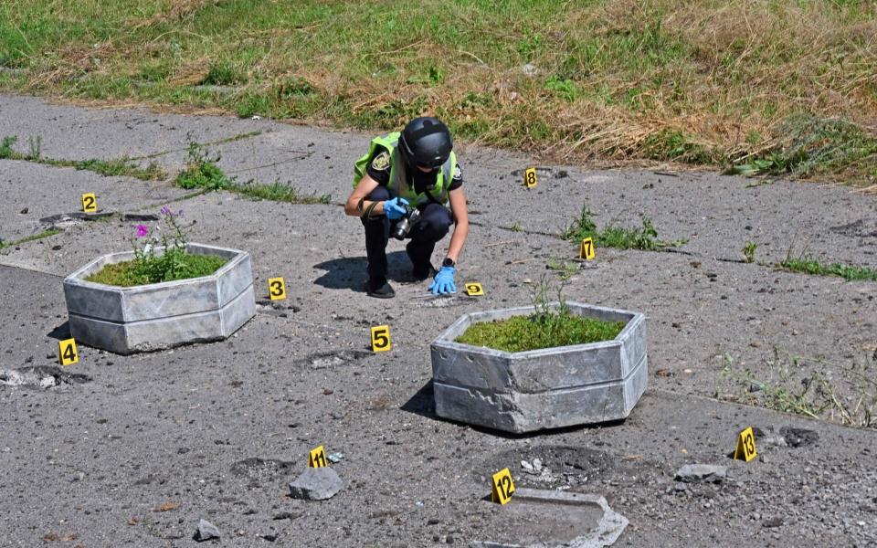 A deminer checks the site of a cluster munition fall after a rocket attack on a residential area in northern Kharkiv - SERGEY BOBOK/AFP