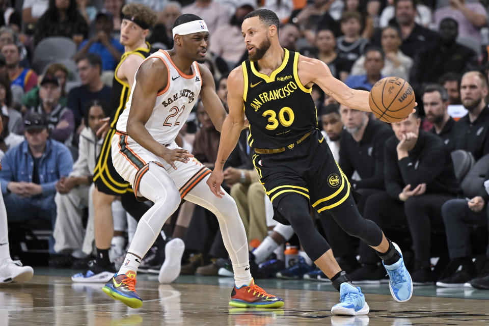 Golden State Warriors' Stephen Curry (30) drives against San Antonio Spurs' Malaki Branham during the first half of an NBA basketball game Sunday, March 31, 2024, in San Antonio. (AP Photo/Darren Abate)