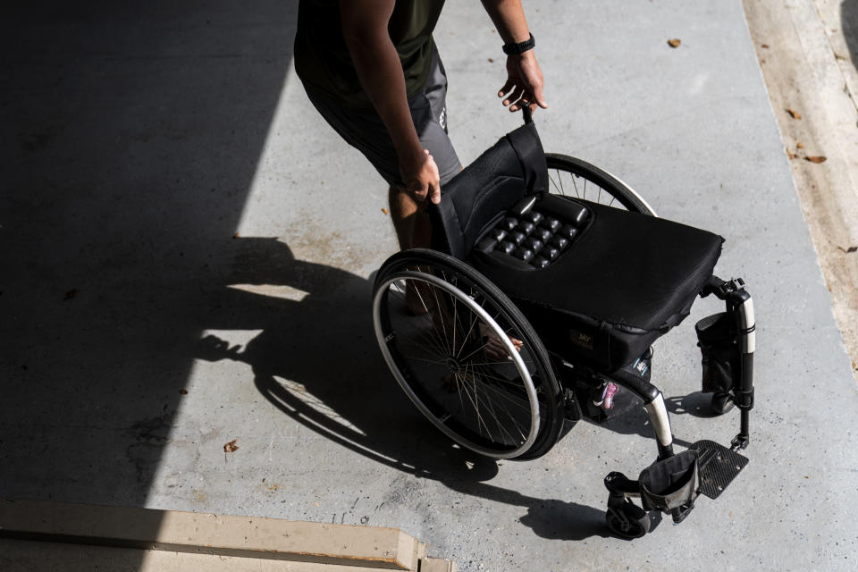 Hunter Paulsen, 20, retrieves a wheelchair from the garage for his mother, Janet, at their home in Acworth, Ga., Monday, Aug. 7, 2023. She was shot six times when her estranged husband ambushed her in their garage in 2015 before he turned the gun on himself. (AP Photo/David Goldman)