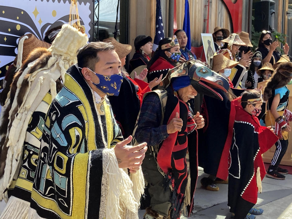 Rico Worl, foreground left, dances during a ceremony on Friday, July 30, 2021, in Juneau, Alaska, that marked the release of a stamp he created for the U.S. Postal Service. Worl, an Alaska Native artist, has said he hopes the Raven Story stamp will be a gateway for people to learn about his Tlingit culture. (AP Photo/Becky Bohrer)