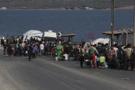 Migrants wait to enter a new temporary refugee camp in Kara Tepe, near Mytilene the capital of the northeastern island of Lesbos, Greece, Thursday, Sept. 17, 2020. Greek police are moving hundreds of migrants to an army-built camp on the island of Lesbos Thursday after a fire destroyed an overcrowded facility, leaving them homeless for days. (AP Photo/Petros Giannakouris)