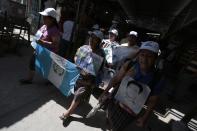 Women from the "Caravana de Madres Centroamericanas" (Caravan of Central American Mothers), with photos of missing migrants and a Guatemalan flag (L), walk to the Suchiate river, to ride a raft to crossover to Guatemala, in the south border of Ciudad Hidalgo, Chiapas, December 18, 2013. According to the organizers, the group which is made up of relatives of people who went missing while making their way to the U.S. went to Mexico in the last two weeks to demand that the governments of Mexico and Central America stop the kidnappings and crimes committed by organised criminal groups against migrants. REUTERS/Jorge Dan Lopez (MEXICO - Tags: CRIME LAW SOCIETY IMMIGRATION POLITICS)