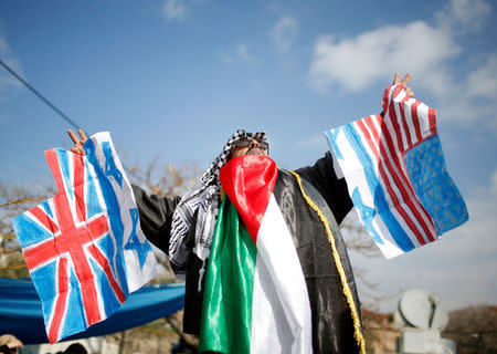 A Palestinian demonstrator gestures as he holds representations of Israeli, British and U.S. flags before burning them during a protest against a U.S. decision to cut aid, in Gaza City January 29, 2018. REUTERS/Mohammed Salem