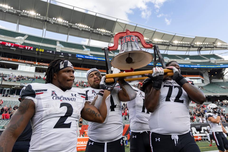 Bearcats players celebrate with the victory bell after defeating Miami 38-17 at Paycor Stadium on Sept. 17, 2022. UC's Ben Bryant threw for 337 yards and a pair of touchdowns.