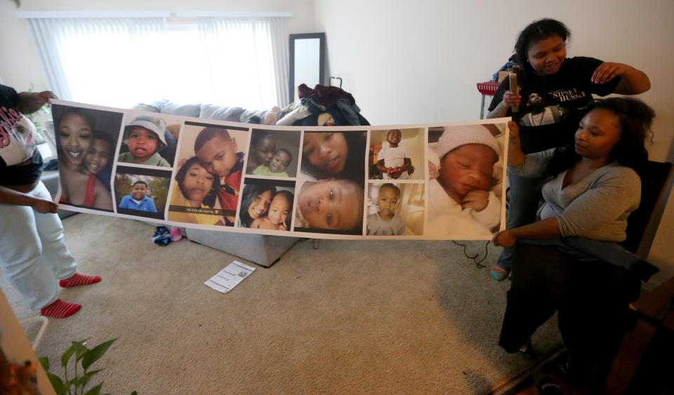 Erika Small and a friend hold a canvas adorned with images of Small's son, 12-year-old Josiah Small. Josiah was shot and killed Oct. 27.