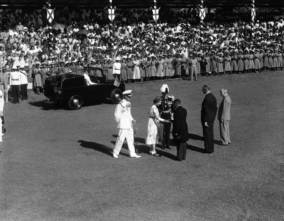 ARCHIVO - En esta foto del 26 de noviembre de 1953, la reina Isabel II de Inglaterra estrecha la mano del ministro de Educación E.L. Allen en Sabina Park, en Kingston, Jamaica, donde la reina y su esposo, el duque de Edimburgo, saludaron a más de 2.000 estudiantes alineados en el campo de cricket del parque. (AP Foto, Archivo)