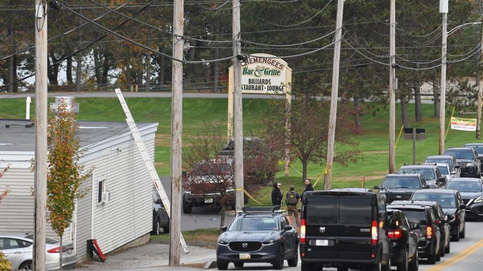 Stopped cars, Schemengees sign, white building, green grass.