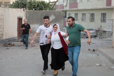 A woman is comforted by her neighboors after a rocket fired from Syria landed in their street in Nusaybin