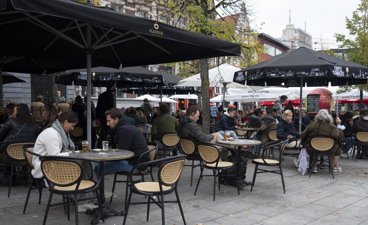 People enjoy drinks on a terrace in the center of Antwerp, Belgium, Saturday, Oct. 17, 2020. Faced with a resurgence of coronavirus cases, the Belgian government on Friday announced new restrictions to try to hold the disease in check, including a night-time curfew and the closure of cafes, bars and restaurants for a month. The measures will take effect on Monday, Oct. 19, 2020. (AP Photo/Virginia Mayo)