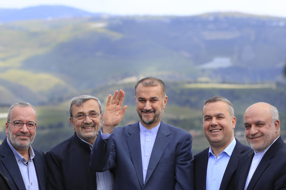 Iranian Foreign Minister Hossein Amirabdollahian, center, waves as he stands with Hezbollah members and lawmakers as the Israeli side seen in the background, during his visit to Iran park, in the village of Maroun el-Rass on the Lebanon-Israel border, south Lebanon, Friday, April 28, 2023. Amirabdollahian visit to Lebanon came after Iran and Saudi Arabia reached an agreement in China last month to re-establish diplomatic relations and reopen embassies after seven years of tension that had major effects on Lebanon. (AP Photo/Mohammed Zaatari)