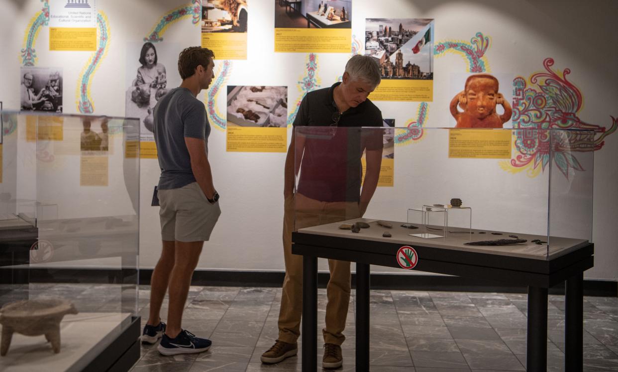 Derek Salas looks over the artifacts inside the glass case while Hank Robson reads the timeline of the artifacts in the "Repatriation and Its Impact" exhibit inside the Parthenon in Nashville, Tenn., Friday, May 3, 2024.