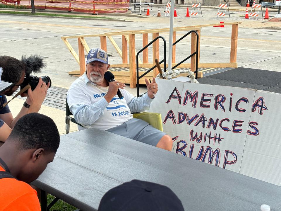 Bob Kunst, 82. from Florida, speaks to a couple of reporters and event staffers during his demonstration at a largely empty Haymarket Square Tuesday morning, one of the designated protest zones in downtown Milwaukee during the Republican National Convention.