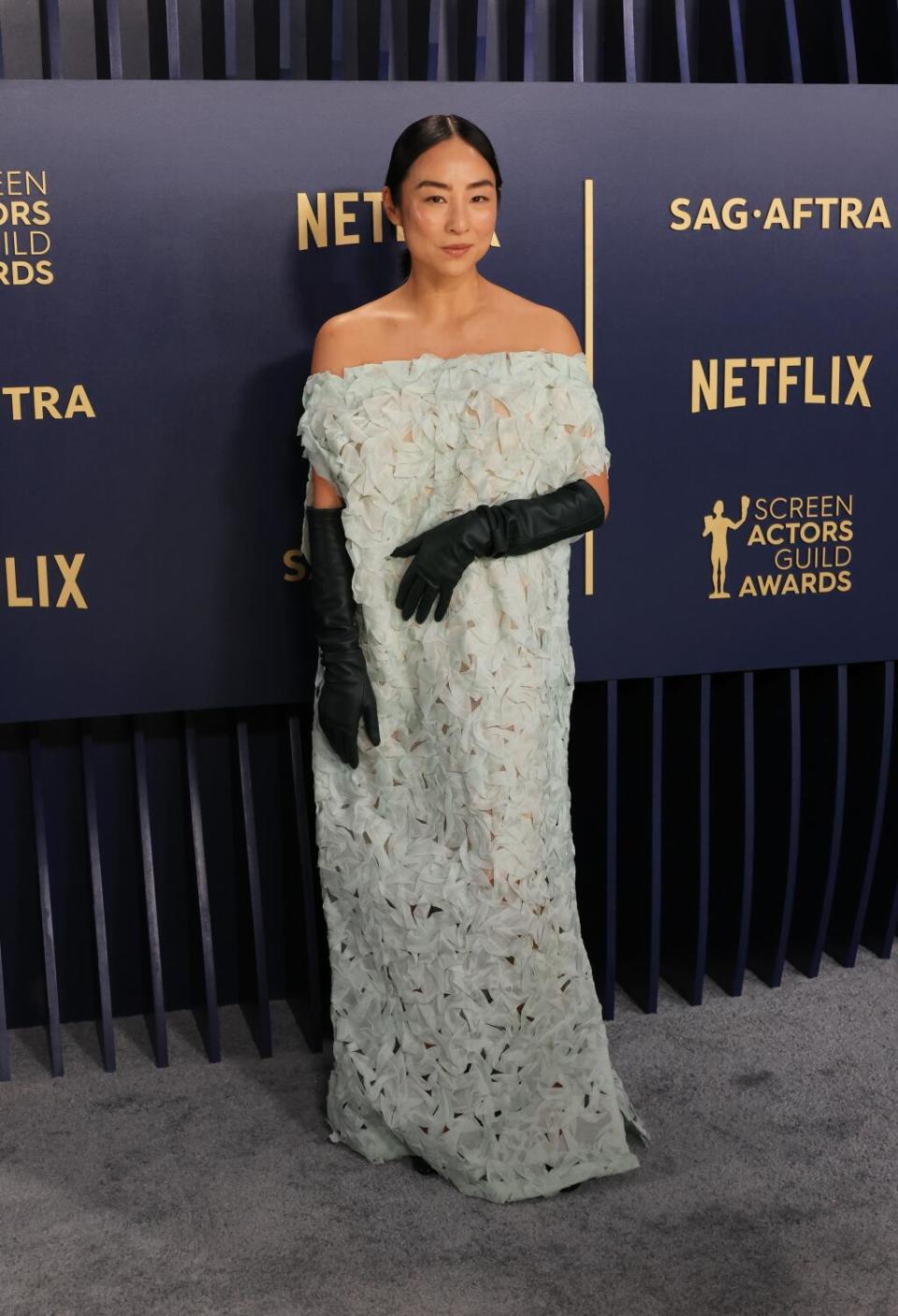 Greta Lee wears a mint green dress with black opera gloves at the SAG Awards.