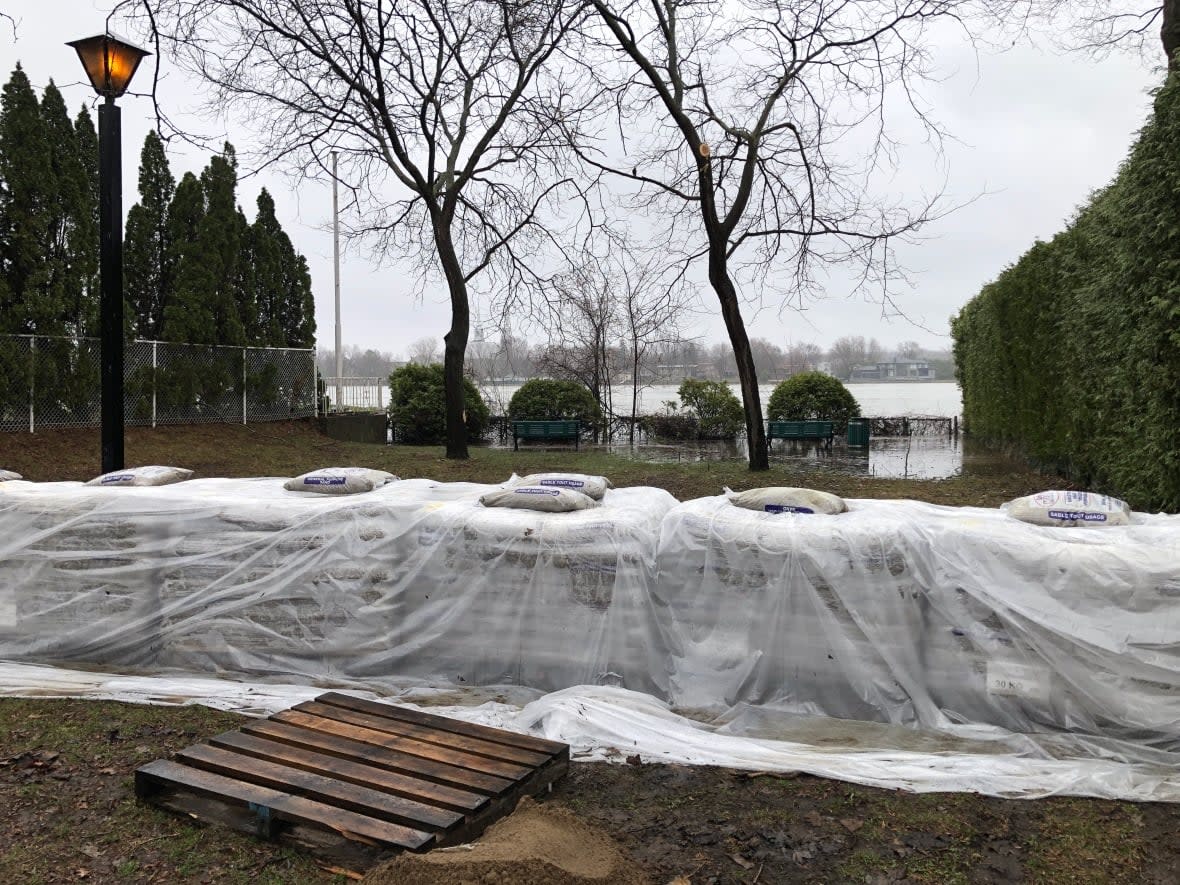 The Rivière des Prairies began to overflow its banks on Monday, spilling into a park on Jean-Yves Street, where workers placed a preventive dike.  (Matt D'Amours/CBC - image credit)