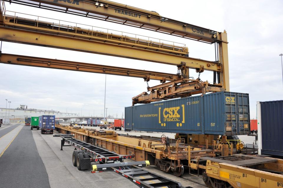 Image shows container cranes, double stack railroad cars, shipping container