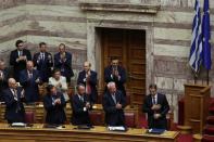 Greek PM Mitsotakis is applauded by his lawmakers and ministers after presenting his government's main policies during a parliamentary session in Athens