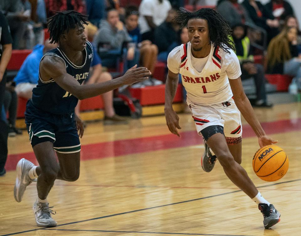 Discovery junior Darius Livingston looks to dribble past McKeel's Alex Sessoms on Thursday night in the semifinals of the Class 4A, District 7 tournament.