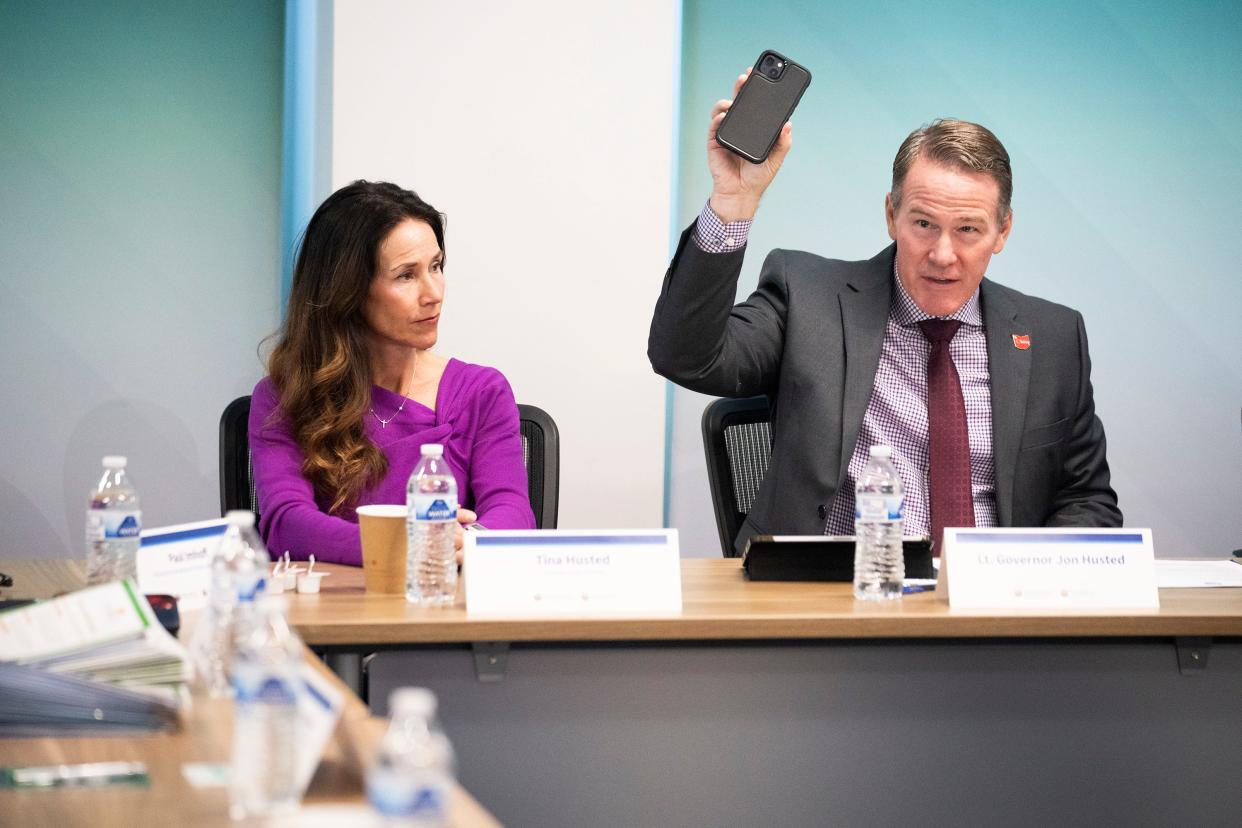 Tina Husted looks to Lt. Gov. Jon Husted as he gestures with a phone as they sit at a roundtable discussion with schools from across the state to discuss how their cellphone policies have created a better learning environment for students and how other Ohio schools could implement their own policies.