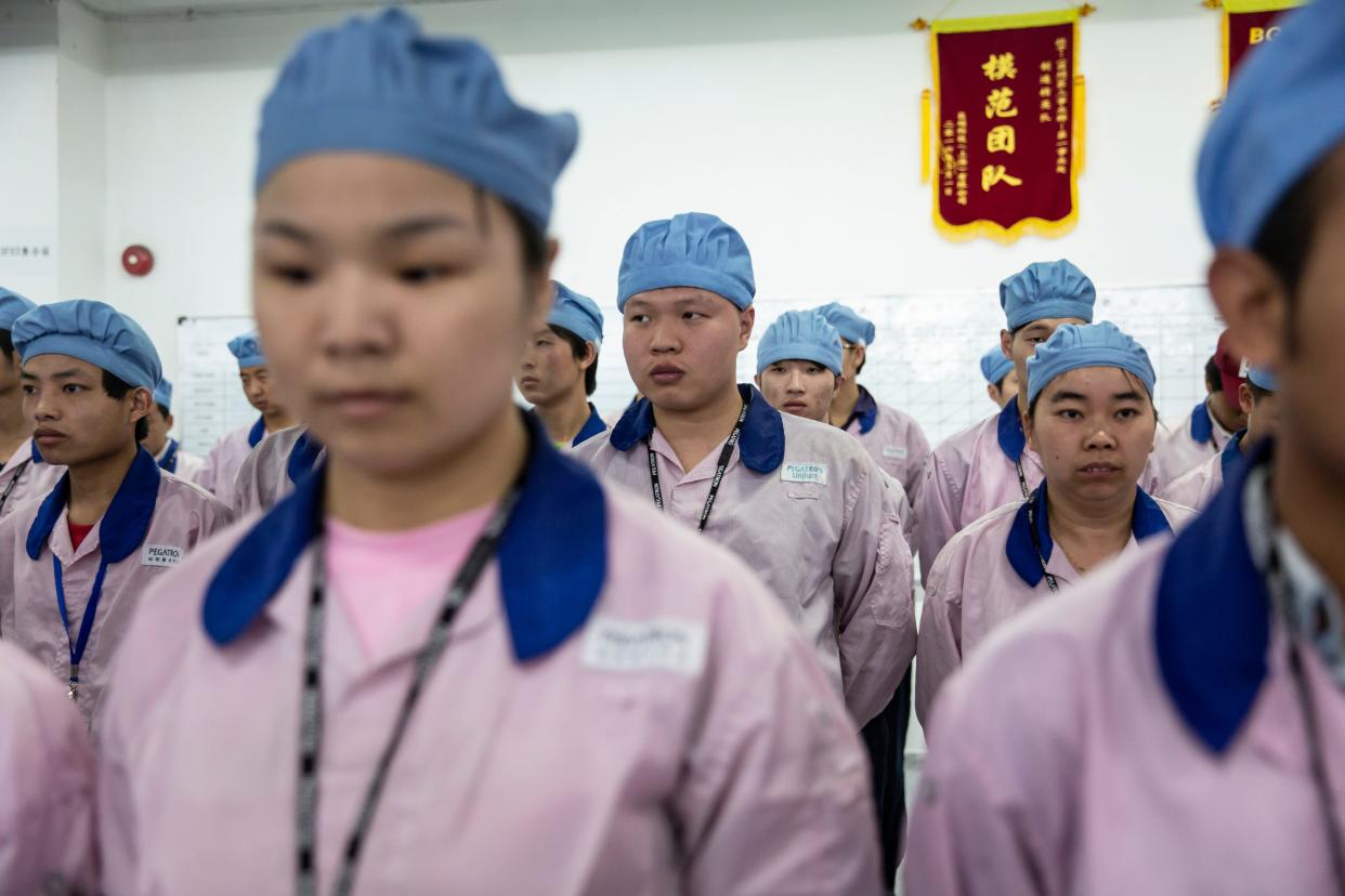 Employees line up for row call before their shift starts at a Pegatron Corp. factory in Shanghai, China, on Friday, April 15, 2016. This is the realm in which the world's most profitable smartphones are made, part of Apple Inc.'s closely guarded supply chain.