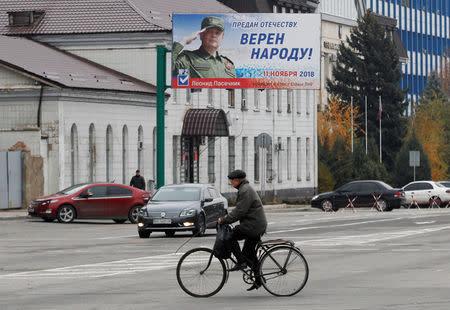 FILE PHOTO: A man rides a bicycle past the campaign board of Leonid Pasechnik, acting head of the self-proclaimed separatist Luhansk People's Republic (LNR), ahead of the upcoming vote for a new leader in Luhansk, Ukraine November 9, 2018. REUTERS/Alexander Ermochenko/File Photo