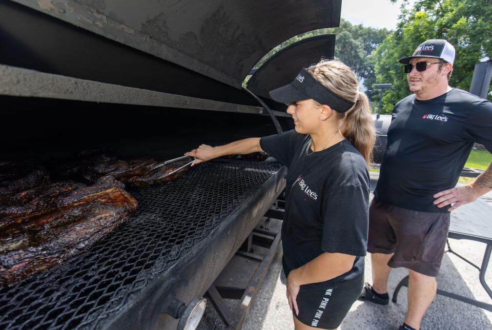 Lily Newlin recently got promoted from team member to kitchen manager. She checks on the briskets with meat/pit manager Bryan Roberts, who also recently got promoted, at the smoke yard for Big Lee's - Serious About BBQ. The smoke yard will provide meats for Big Lee's new permanent restaurant space, which opens on the 4th of July, and for the food trucks.