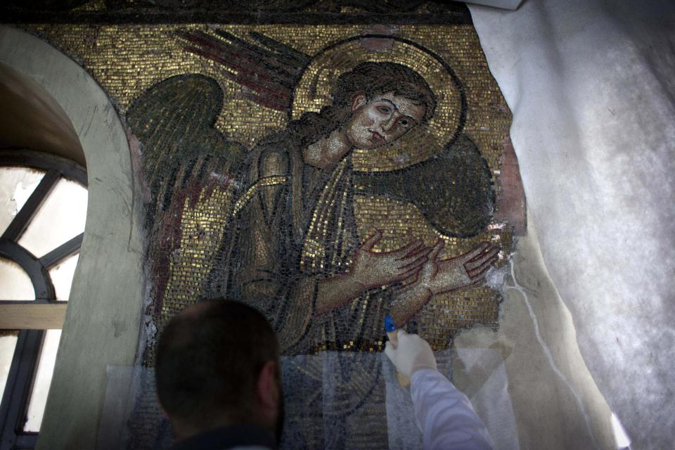 In this Tuesday Dec. 10, 2013 photograph, a restoration expert works on a mosaic inside the Church of the Nativity in the West Bank city of Bethlehem. To visitors arriving in Bethlehem for Christmas this year the Nativity Church will look different. Wrapped in scaffolding, the basilica is having a much-needed facelift after 600 years. Last year it has been included in UNESCO's list of endangered World Heritage sites. (AP Photo/Nasser Nasser)